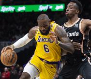 LeBron James, alero de Lakers de Los Ángeles, ataca rumbo a la canasta ante la marca defensiva de Onyeka Okongwu, de los Hawks de Atlanta, durante la primera mitad del juego de baloncesto de la NBA, el viernes 30 de diciembre de 2022, en Atlanta. (AP Foto/Hakim Wright Sr.)