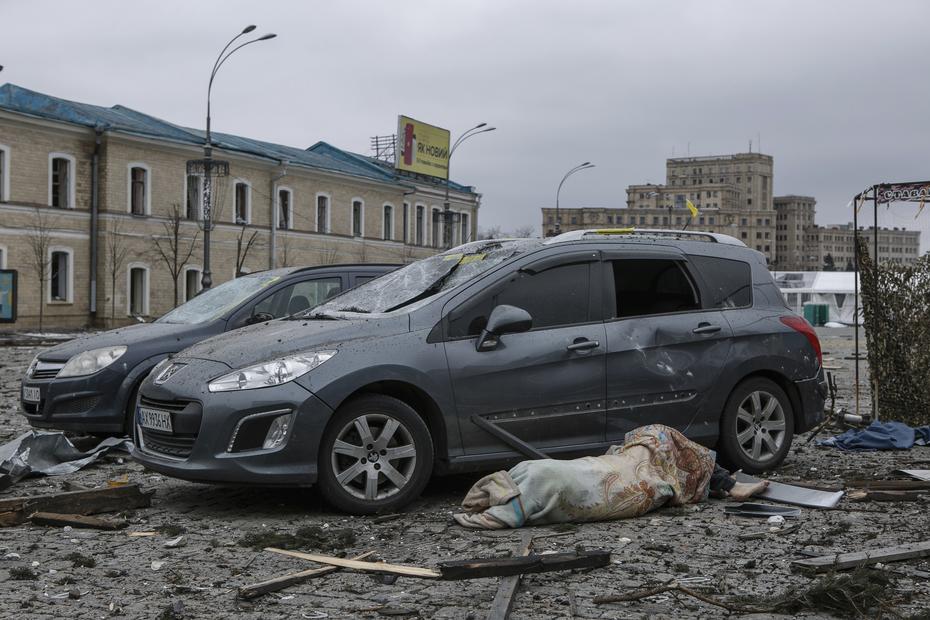 El cuerpo de una víctima yace junto a los autos dañados en la plaza central tras el bombardeo del edificio del Ayuntamiento en Kharkiv, Ucrania
