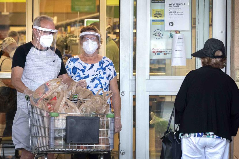 Una pareja de ancianos sale de hacer compras en un supermercado en Miami. (EFE)
