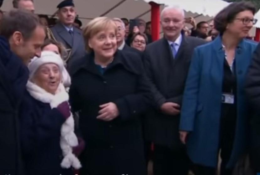 El presidente francés, Emmanuel Macron (i), y la canciller alemana, Angela Merkel (d), se fotografían con una anciana (c) durante el acto de conmemoración de la firma del armisticio que puso fin a la Gran Guerra en 1918. (Captura)