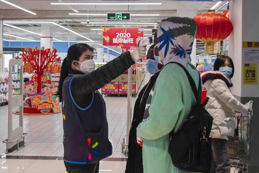 Una empleada de un Walmart en Wuhan le toma la temperatura a un cliente. (AP)