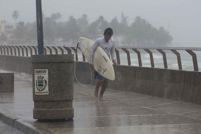 Un surfer corre por una acera mientras llueve. (GFR Media)