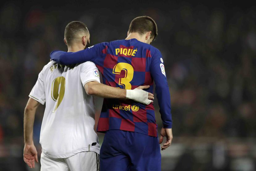 Karim Benzema, izquierda, del Real Madrid, camina junto a Gerard Piqué, del Barcelona, al final del clásico de La Liga en el Camp Nou de Barcelona. (AP)