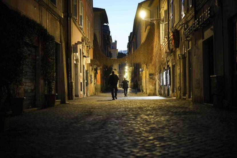 Imagen de dos personas caminando por un callejón desolado en Roma. (AP)