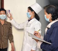 En esta imagen de archivo, distribuida por el gobierno de Corea del Norte, una doctora toma la temperatura a un residente para tratar de frenar la propagación del coronavirus, en Piongyang.