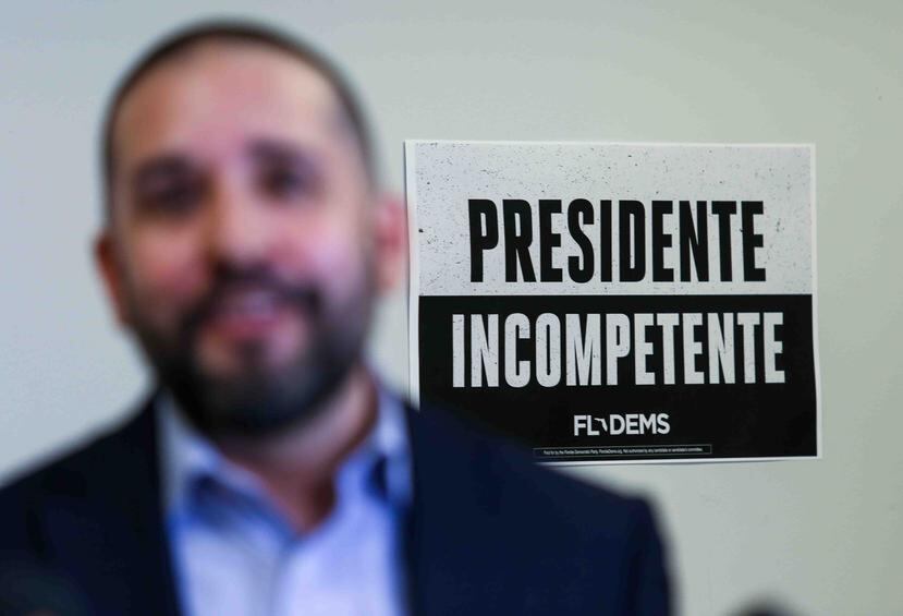Juan Peñalosa, director ejecutivo del Partido Demócrata de Florida, muestra una pegatina con la frase "Presidente Incompetente".