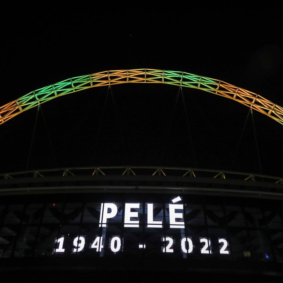 El arco de Wembley se ilumina con los colores de la selección brasileña, encima de un letrero que anuncia la muerte de Pelé.