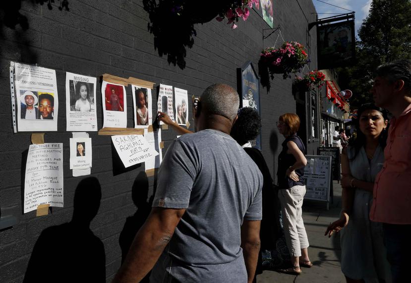 Papeles con fotos de personas desaparecidas cuelgan en una pared cercana a la Torre Grenfell. (AP)