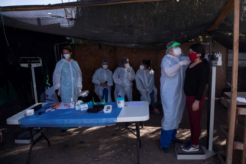 Trabajadores de la organización TECHO-Chile prestan asistencia sanitaria a los habitantes del campamento Millantu, en la comuna de Puente Alto de Santiago en Chile. (AP)