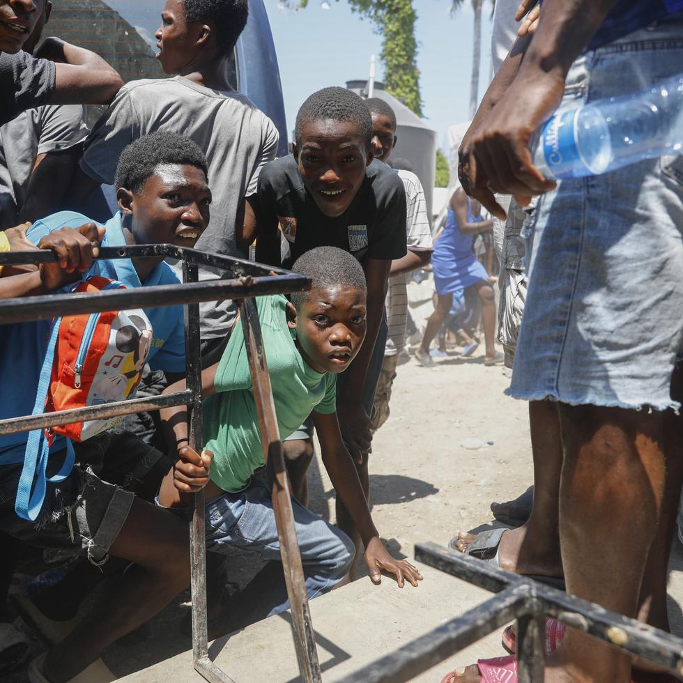 Unos jóvenes se agachan tras escuchar disparos en una escuela que sirve de albergue para personas desplazadas por la violencia de las pandillas, en Puerto Príncipe, Haití.