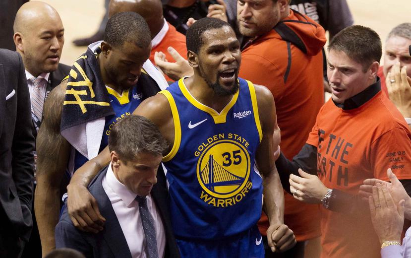 Kevin Durant, alero de los Warriors de Golden State, es ayudado a salir de la cancha tras lesionarse durante el quinto partido de la Final de la NBA. (Chris Young/The Canadian Press via AP)