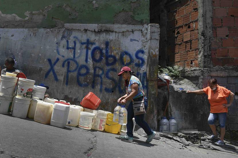 Una mujer cargando dos contenedores de agua en el barrio pobre de Petare, en Caracas, Venezuela. (AP)