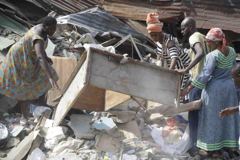 Varias personas ayudan a mover los escombros luego del colapso de la escuela. (AP / Sunday Alamba)
