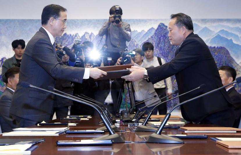El ministro de Unificación surcoreano, Cho Myoung-gyon (i), y el presidente del Comité para la Reunificación Pacífica de Corea del Norte, Ri Son-gwon, intercambian documentos tras una reunión en la fronteriza aldea de Panmunjom, Corea del Sur. (EFE)