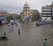 Motociclistas y peatones vadean una calle inundada en un distrito financiero de Karachi, Pakistán, el sábado 9 de julio de 2022. (AP Foto/Fareed Khan)