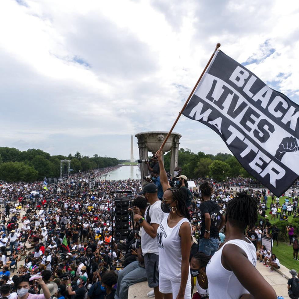 A woman holds a "Black Lives Matter," flag during the March on Washington, Friday Aug. 28, 2020, at the Lincoln Memorial in Washington, on the 57th anniversary of the Rev. Martin Luther King Jr.'s "I Have A Dream" speech. (AP Photo/Alex Brandon)