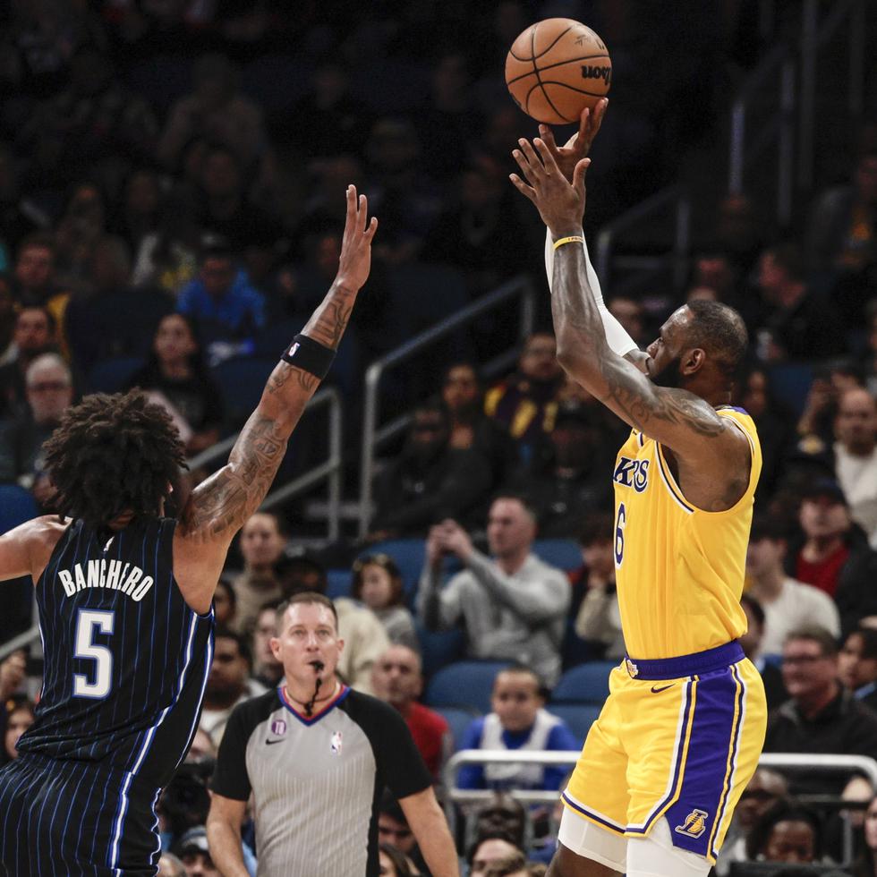 El alero de los Lakers de Los Ángeles LeBron James lanza el balón sobre el alero del Magic de Orlando Paolo Banchero en el encuentro del martes 27 de diciembre del 2022.
