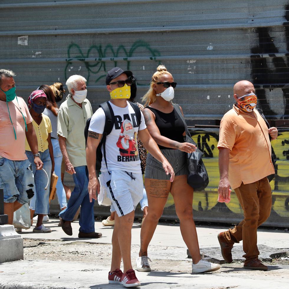 Varias personas con tapabocas caminan por una calle de La Habana.