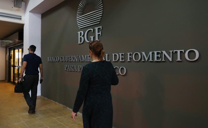 A woman walks in front of the logo of the Government Development Bank. (GFR Media)