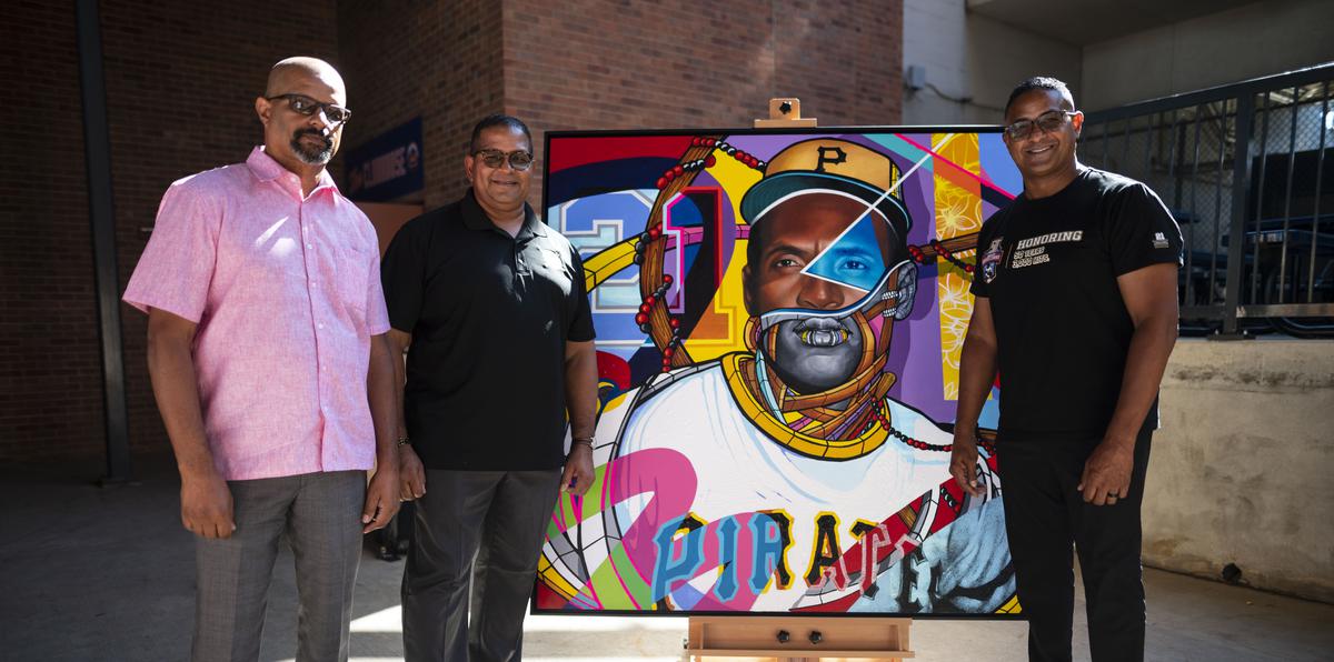 Roberto Enrique, Luis Roberto y Roberto Clemente, Jr. posan al lado de una obra realizada por el artista boricua David “Don Rimx” Sepúlveda.