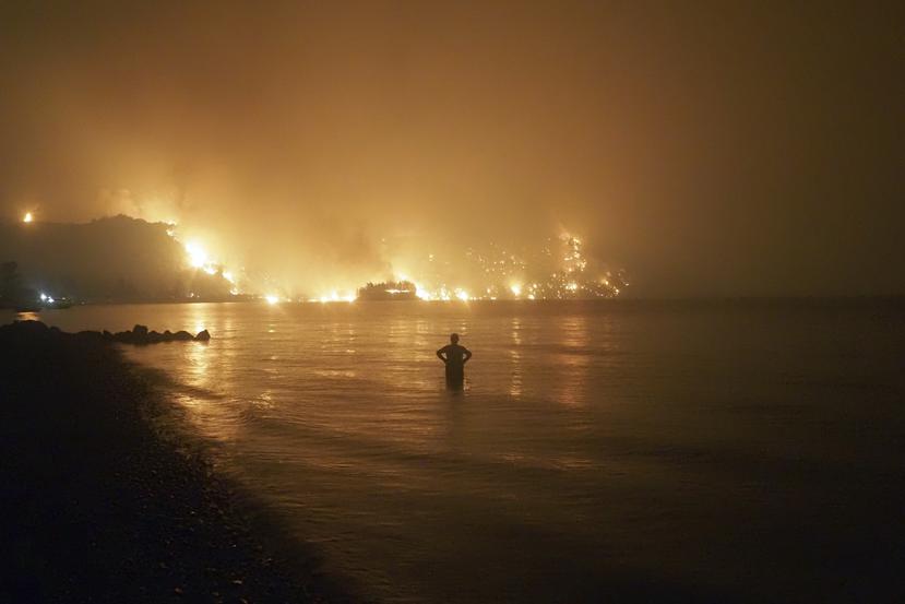 Un hombre observa un incendio cerca de la playa de Kochyli cerca del pueblo de Limni, en la isla de Evia, a unos 160 kilómetros (100 millas) al norte de Atenas, la noche del viernes 6 de agosto de 2021.