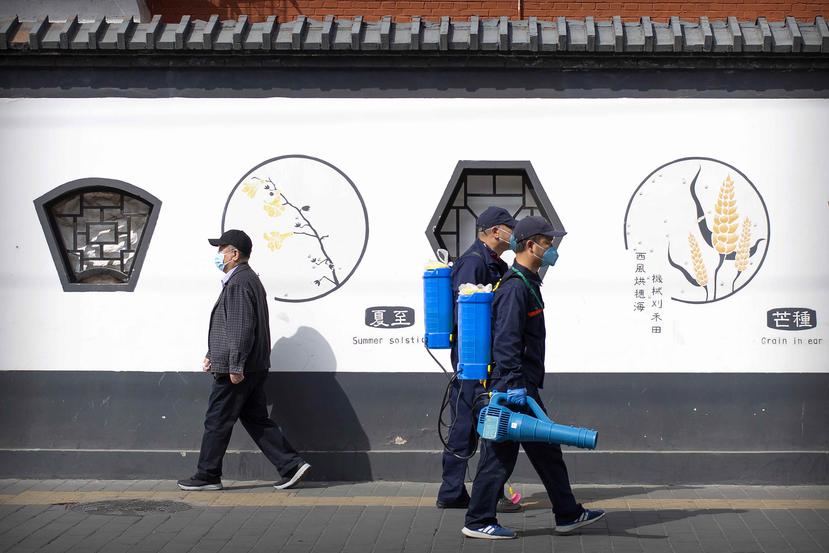 Trabajadores utilizan mascarillas protectoras mientras realizan labores de limpieza en una calle de Beijing. (AP)