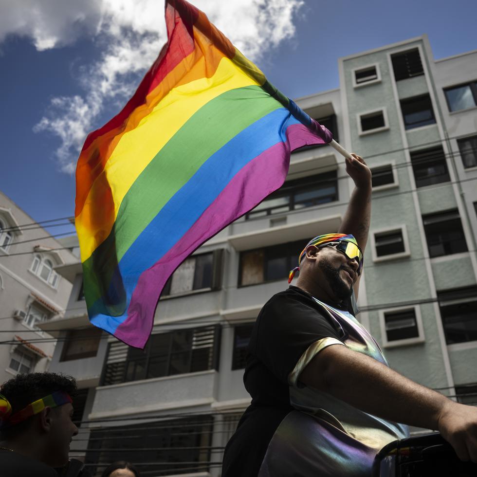 Uno de los participantes de la Parada Orgullo Gay en San Juan, sostiene la bandera multicolor que identifica a la comunidad.