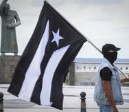 Un manifestante carga la bandera de "luto" de Puerto Rico.