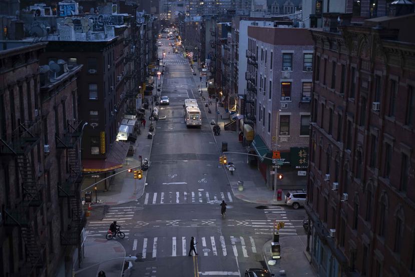 Biciclistas y un peatón pasan por una tranquila calle de Manhattan. (AP)