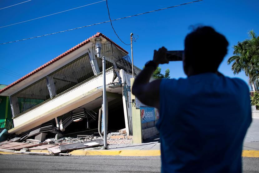 Una persona le toma una foto a una residencia que colapsó a causo de los terremotos.