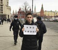 Policías rusos se aprestan a detener a Dimitry Reznikov, que lleva una hoja de papel con ocho asteriscos que pudieran ser interpretados como "No a la guerra", con el Kremlin como trasfondo.