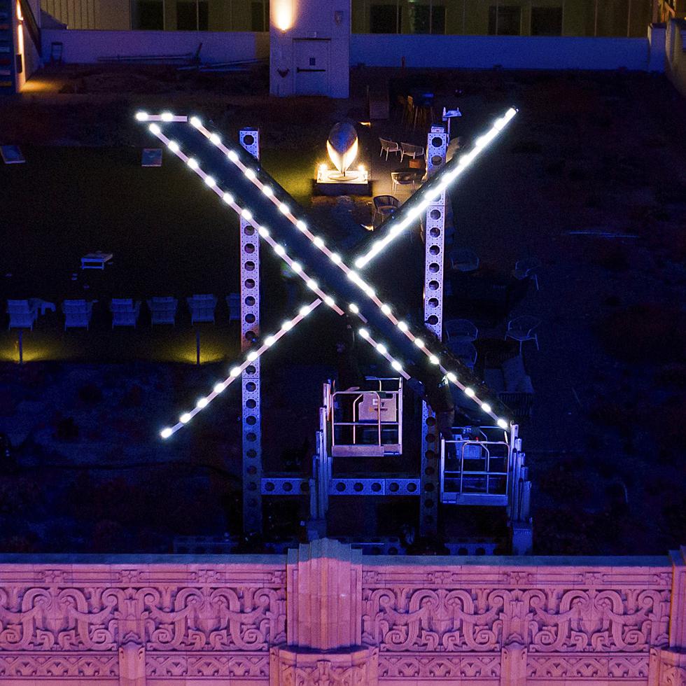 Trabajadores instalan luces en un letrero de "X" encima de la sede de la compañía, anteriormente conocida como Twitter, el 28 de julio de 2023, en San Francisco. (AP Foto/Noah Berger, archivo)