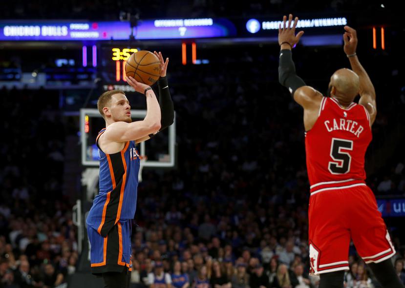 El base de los Knicks de Nueva York Donte DiVincenzo se prepara para lanzar un triple frente a Jevon Carter, de los Bulls de Chicago.