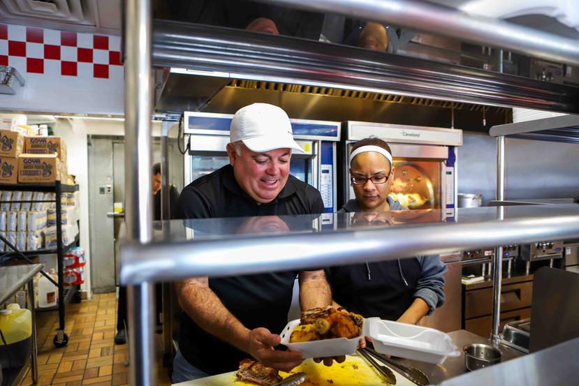 Arturo Norat codueño de Víktor Pollo en Kissimmee, sirve una amplia porción de pollo asado para un cliente.