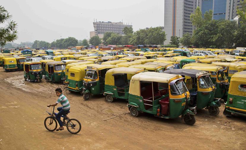 Un jovencito corre junto a los vehículos de tres ruedas en Nueva Delhi. (AP)