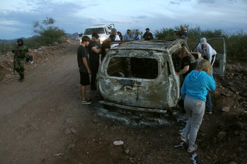 Miembros de la familia LeBarón observan el vehículo calcinado donde fueron asesinados sus familiares. (EFE)