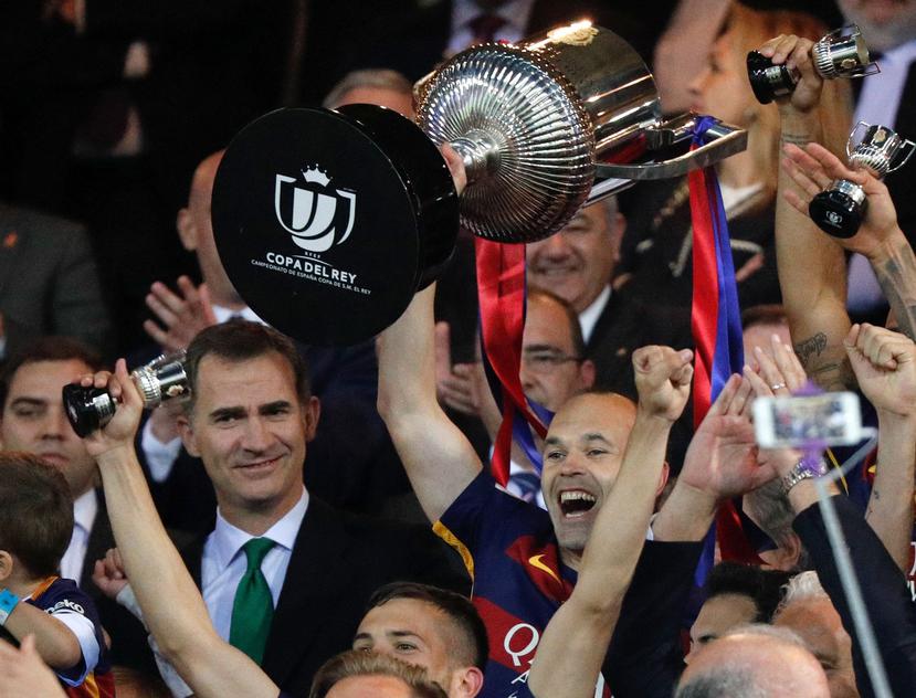 El capitán del FC Barcelona Andrés Iniesta (d), junto al rey Felipe VI, levanta la Copa del Rey tras vencer en la final al Sevilla FC por 2-0, esta noche en el estadio Vicente Calderón. (EFE)