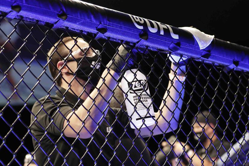 Personal de UFC desinfecta la jaula entre peleas. (AP)