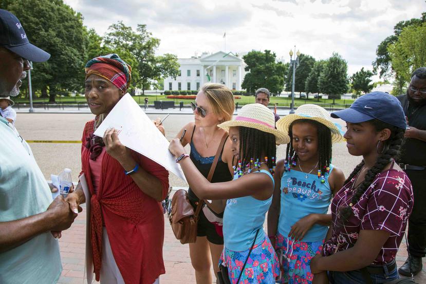 Arnelle Hardy, izquierda, pide a la gente en el parque Lafayette al otro lado de la calle de la Casa Blanca que envíe mensajes de aliento a la familia de la cantante Aretha Franklin. (AP)