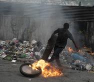 Un manifestante patea un neumático en llamas durante una protesta en Puerto Príncipe, Haití, el lunes 22 de agosto de 2022. (AP Foto)