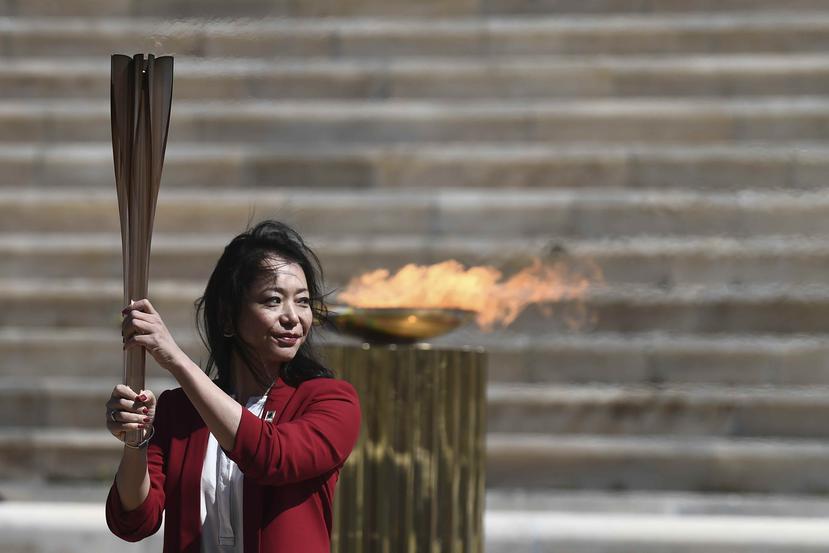 La exnadadora japonesa Imoto Naoko sostiene la antorcha olímpica durante la ceremonia de entrega de la llama para los Juegos Olímpicos de Tokio 2020. (AP)