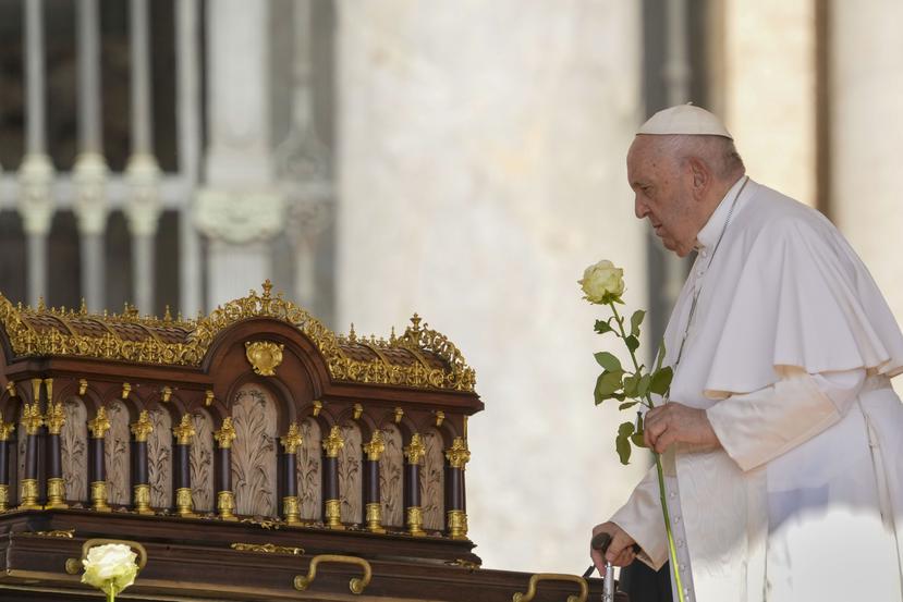 El papa Francisco, con una rosa en la mano, se dispone a rezar ante las reliquias de Santa Teresa del Niño Jesús, patrona universal de las misiones (izquierda), a su llegada a la audiencia nacional en la Plaza de San Pedro, en el Vaticano, el 7 de junio de 2023.