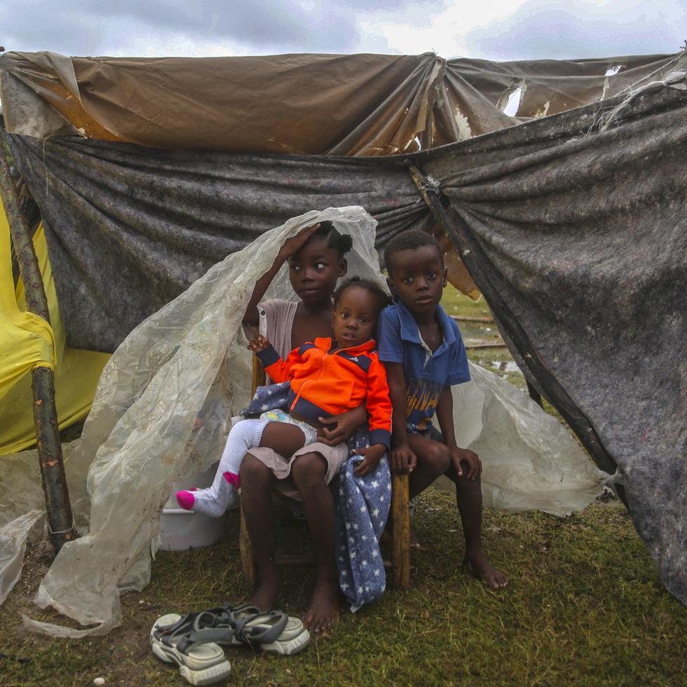 Earthquake-displaced children huddle under a piece of plastic the morning after Tropical Storm Grace swept over Les Cayes, Haiti, Tuesday, Aug. 17, 2021, three days after a 7.2-magnitude earthquake. (AP Photo/Joseph Odelyn)