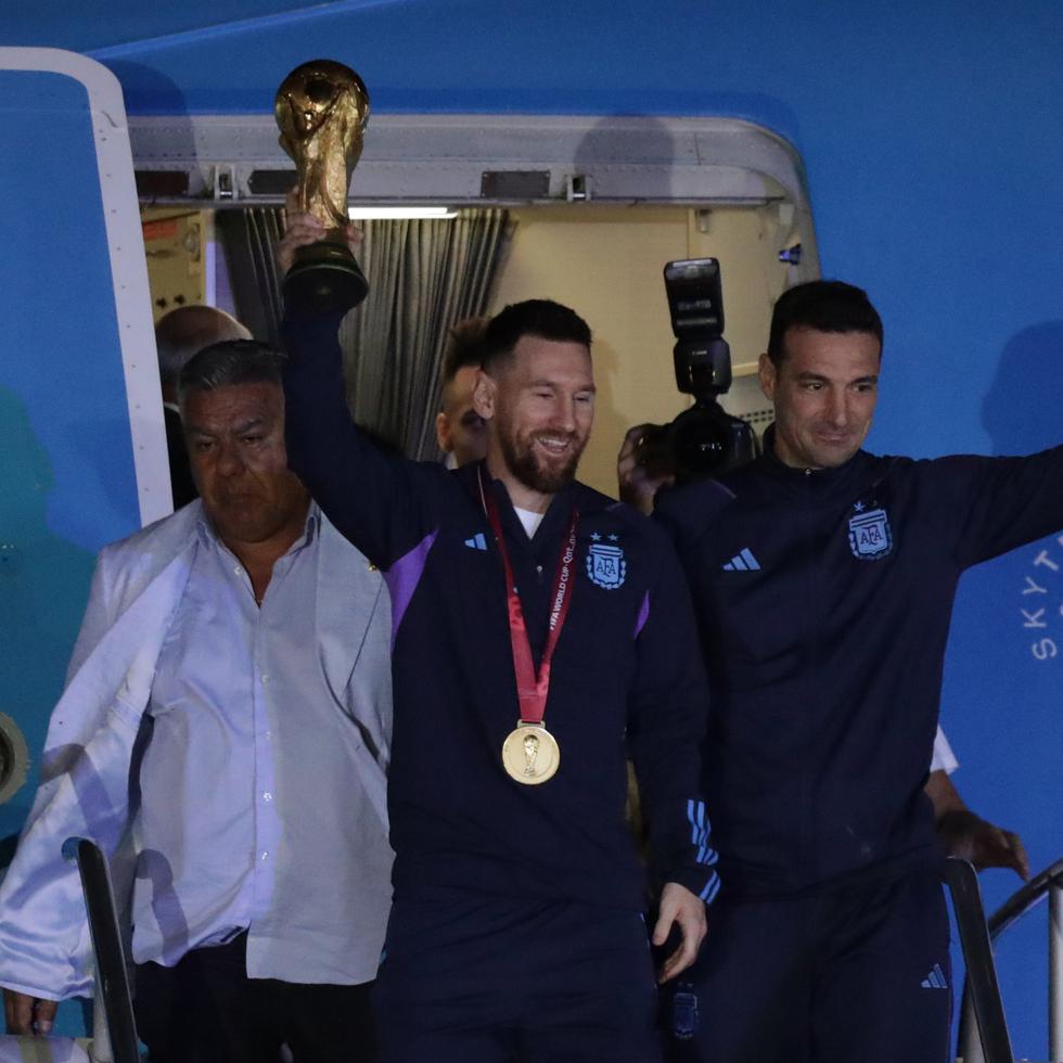 Lionel Messi, de la selección argentina de fútbol, saluda con el trofeo del Mundial de Catar 2022 junto al seleccionador Lionel Scaloni (derecha) a su llegada al Aeropuerto Internacional de Ezeiza.