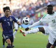 Mbaye Niang, de Senegal, busca manejar el balón contra Gaku Shibasaki y Gen Shoji. (AP)