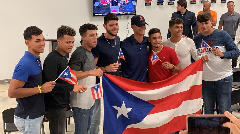 Matthew Lugo, al centro con la gorra de Boston, esperó la noticia de su selección en la Carlos Beltrán Baseball Academy, rodeado de compañeros y familiares. (Suministrada / CBBA)
