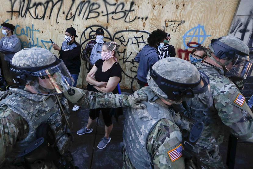 Personal de la Guardia Nacional regresa a su posición de defensa mientras los manifestantes dejan espacio para que retrocedan luego de una confrontación en el área de East Lake Street, en Minneapolis. (AP)