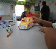 Un estudiante juega con una guagua de juguete en un salón de clases.