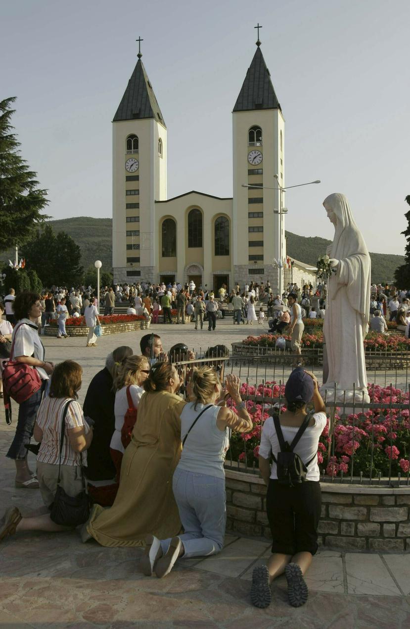 Peregrinos rezan alrededor de una estatua de la Virgen María frente a la Iglesia de Santiago en Medjugorje, Bosnia y Herzegovina. (AP)