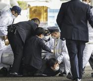 Varios policías sujetan a un hombre tras derribarlo, después de que supuestamente arrojó un objeto explosivo hacia el primer ministro japonés.
